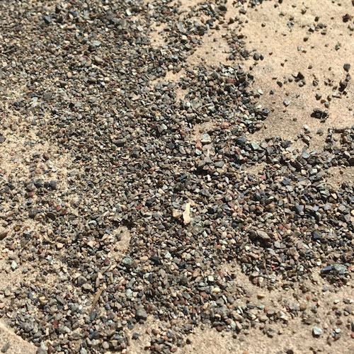 close-up of loose roofing shingle granules on ground