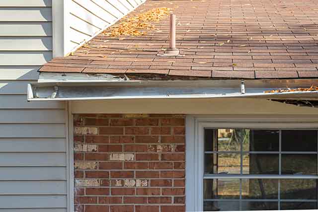 a sagging gutter on house with a rotting facia board